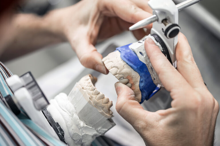 Dental technician working with tooth dentures at prosthesis laboratory